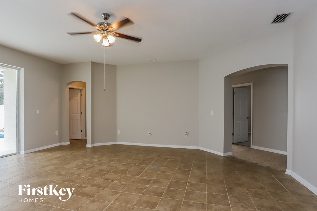 an empty living room with a ceiling fan