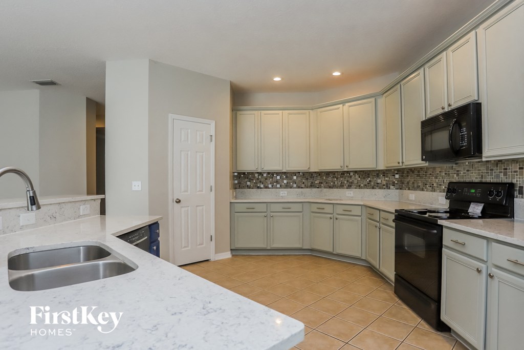 a kitchen with white cabinets and black appliances and a sink