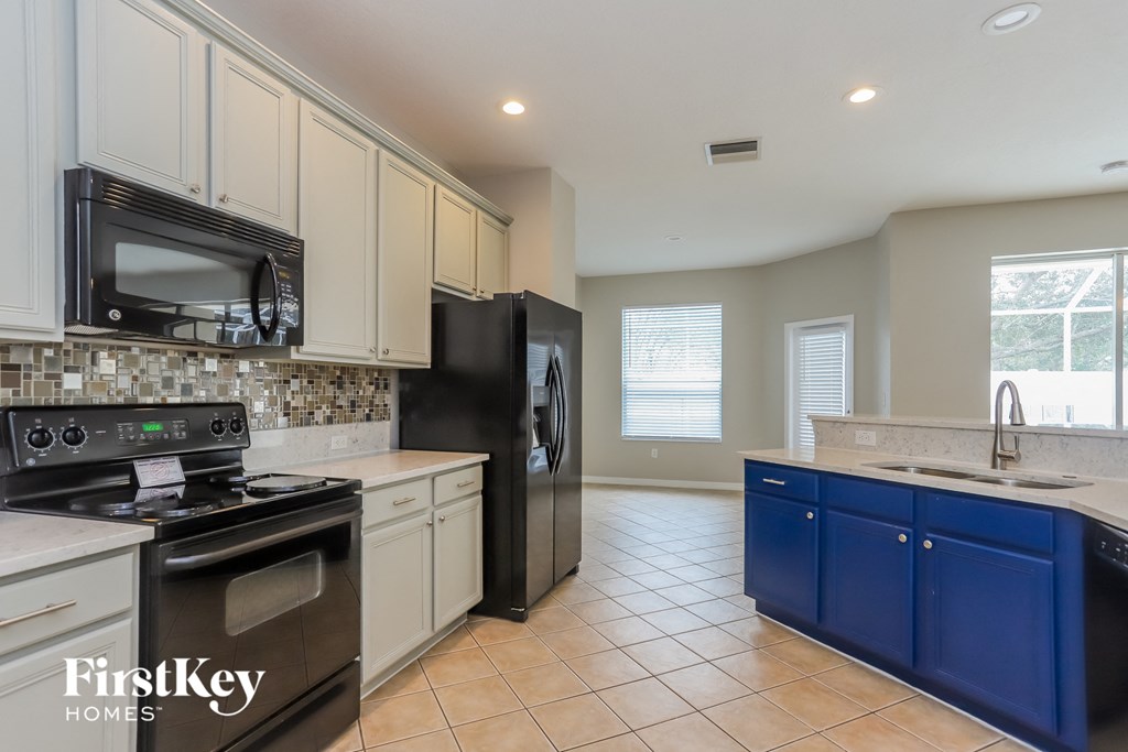 a kitchen with white cabinets and black appliances