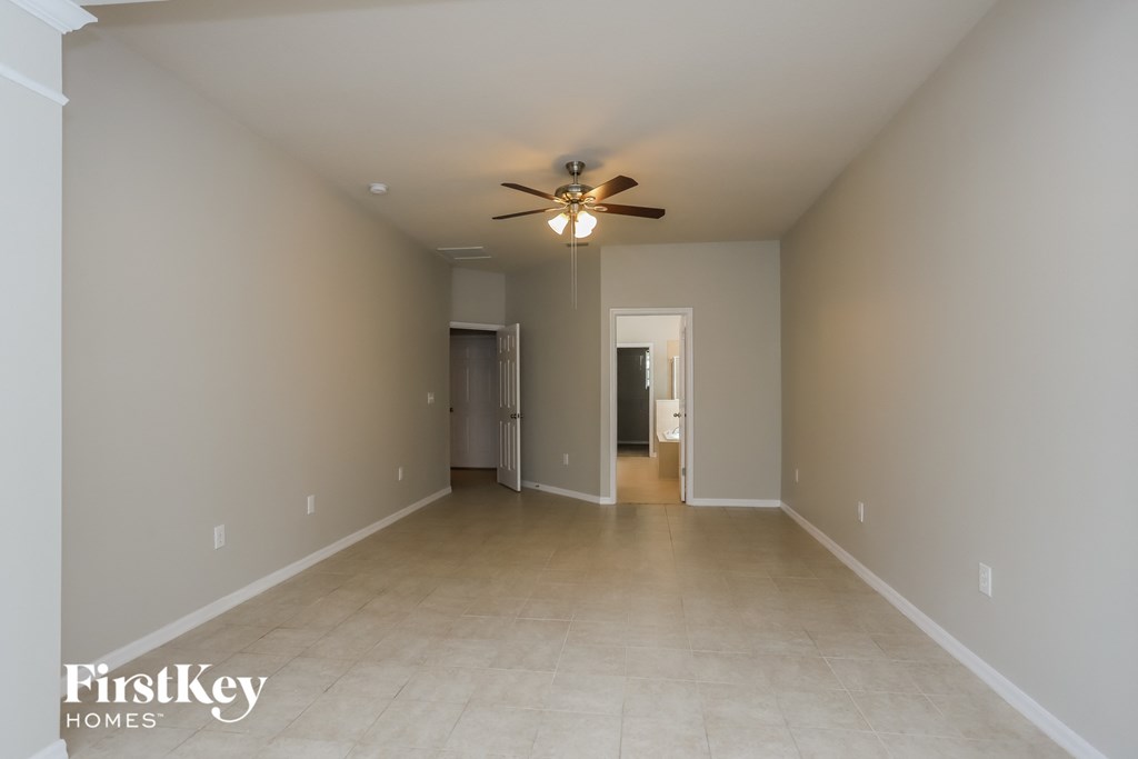 a spacious living room with neutral walls and a ceiling fan