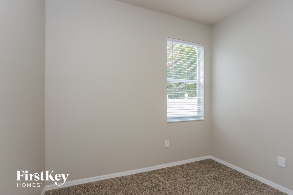 a room with white walls and a window with blinds