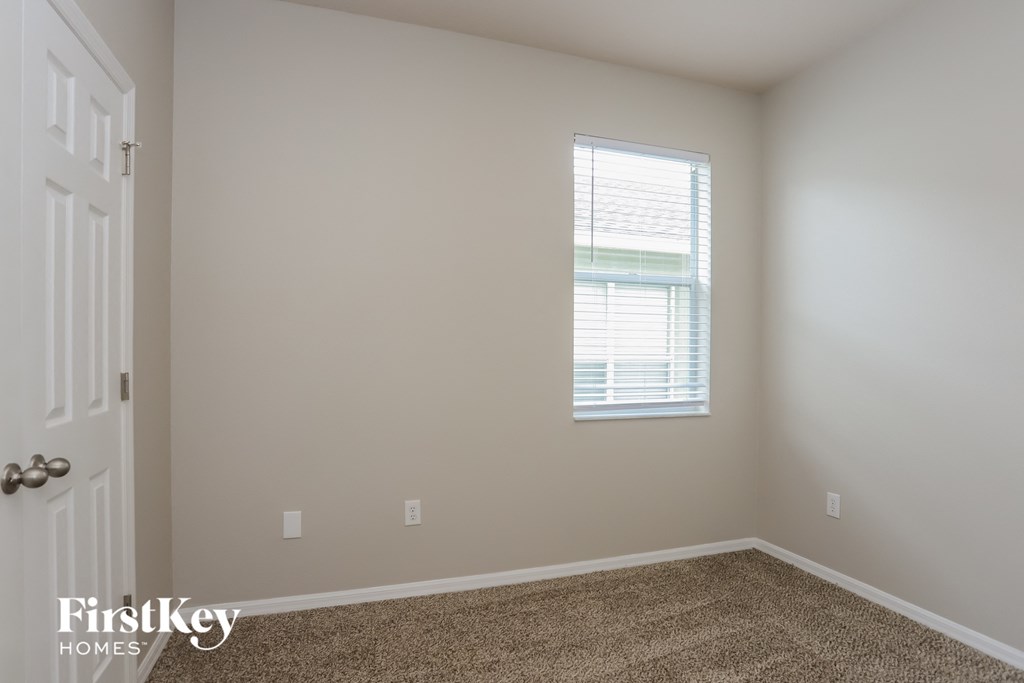 a bedroom with a window and a carpeted floor