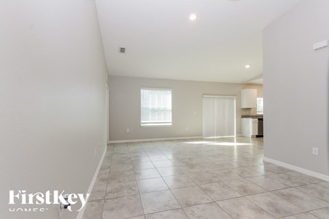 A spacious empty room with a large window and tiled floor.