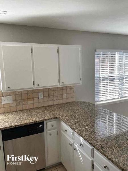 a kitchen with white cabinets and a granite counter top