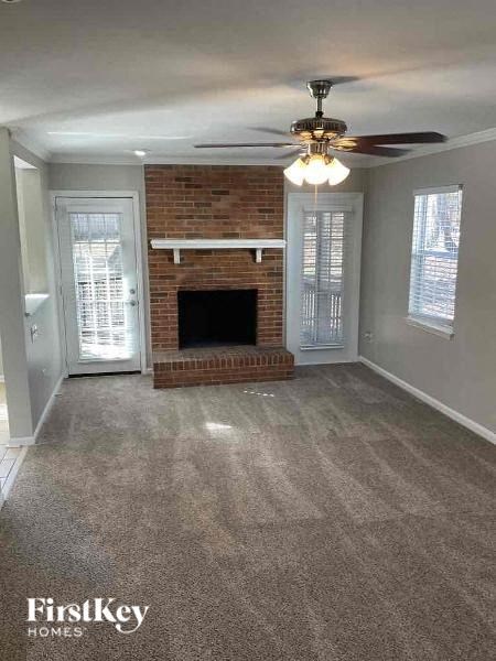 an empty living room with a fireplace and a ceiling fan