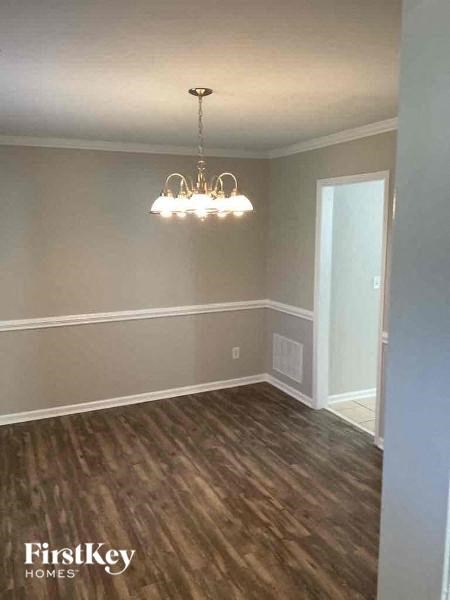a empty dining room with a chandelier and wood floors