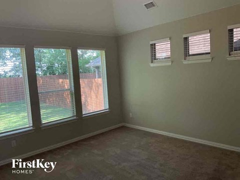 a bedroom with three windows and a carpeted floor