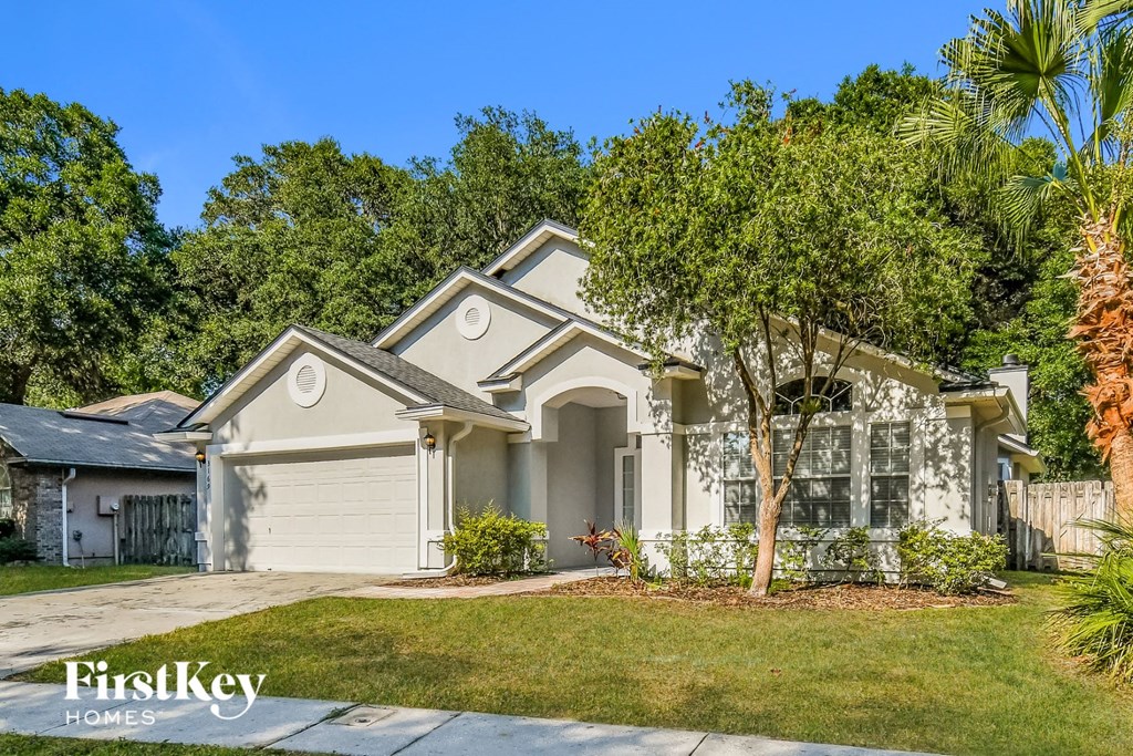 a house with a driveway and trees in front of it