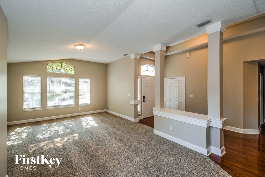 an empty living room with white pillars and a white door
