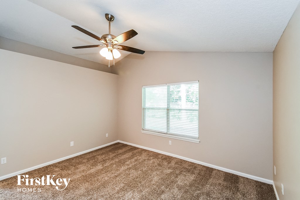 the spacious living room has a ceiling fan and a large window