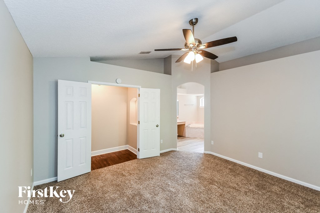 the living room is spacious and has a ceiling fan