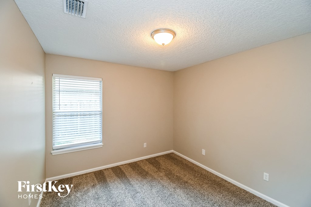 the upstairs bedroom has a carpeted floor and a window
