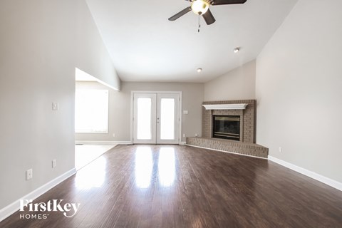 an empty living room with a fireplace and a ceiling fan