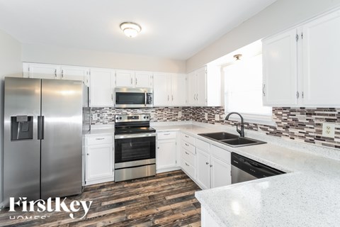 A kitchen with a refrigerator, oven, sink, and cabinets.