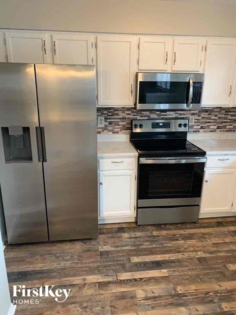 a kitchen with white cabinets and a stainless steel refrigerator
