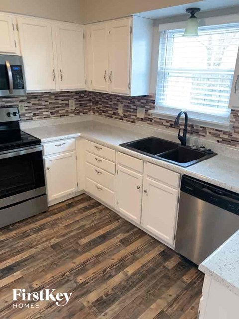 a kitchen with wooden floors and white cabinets and a sink