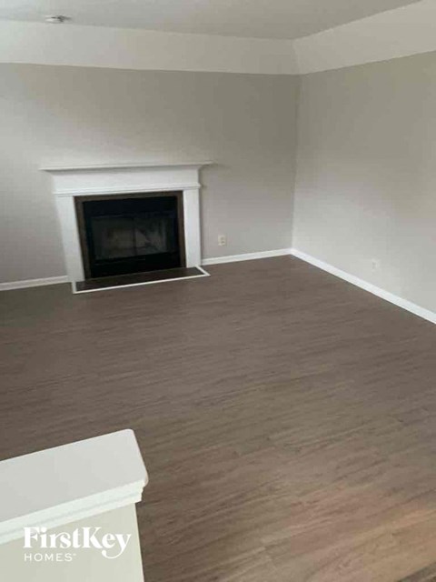 an empty living room with wood flooring and a fireplace