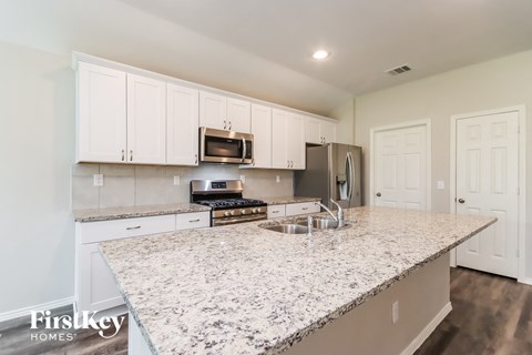 a kitchen with white cabinets and a marble counter top