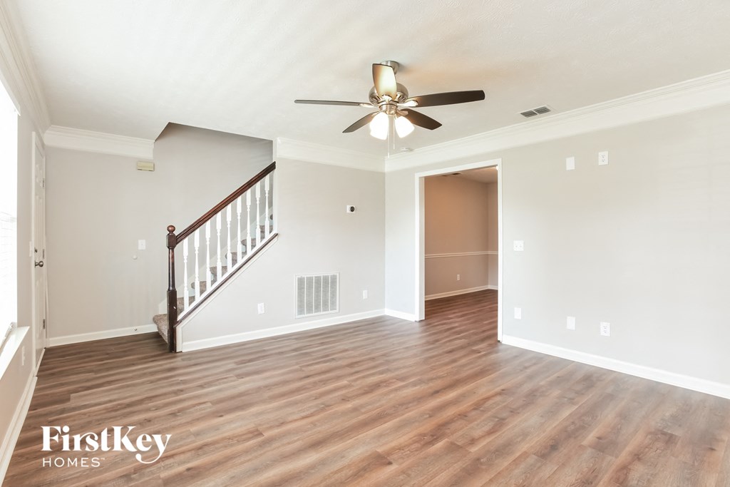 A spacious room with a wooden floor and a ceiling fan.