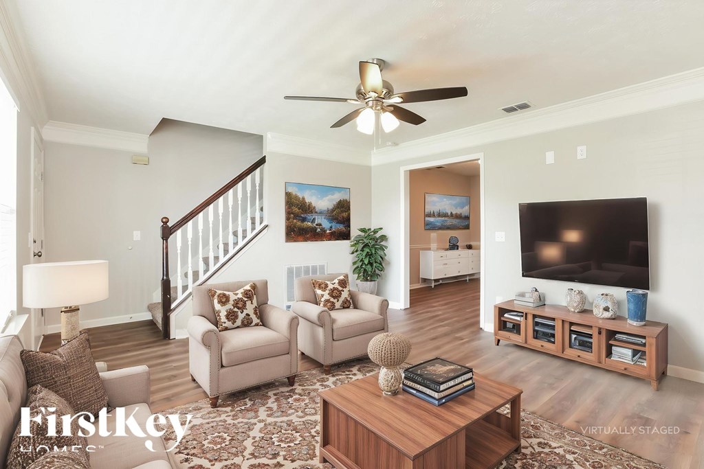 A living room with a staircase and a flat screen TV.