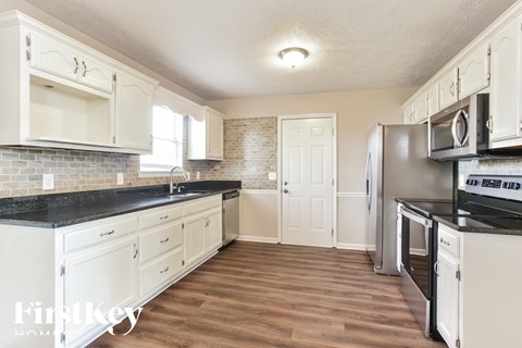A kitchen with white cabinets and a black countertop.