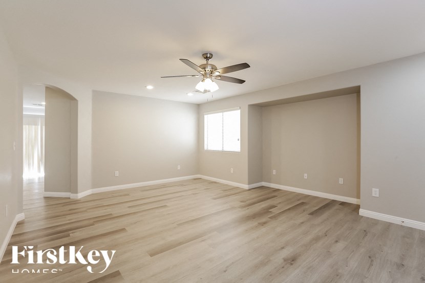 A spacious room with wooden floors and a ceiling fan.