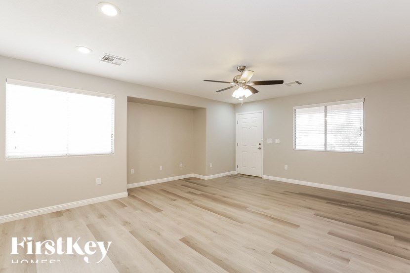 A spacious room with a ceiling fan and lighting fixtures.
