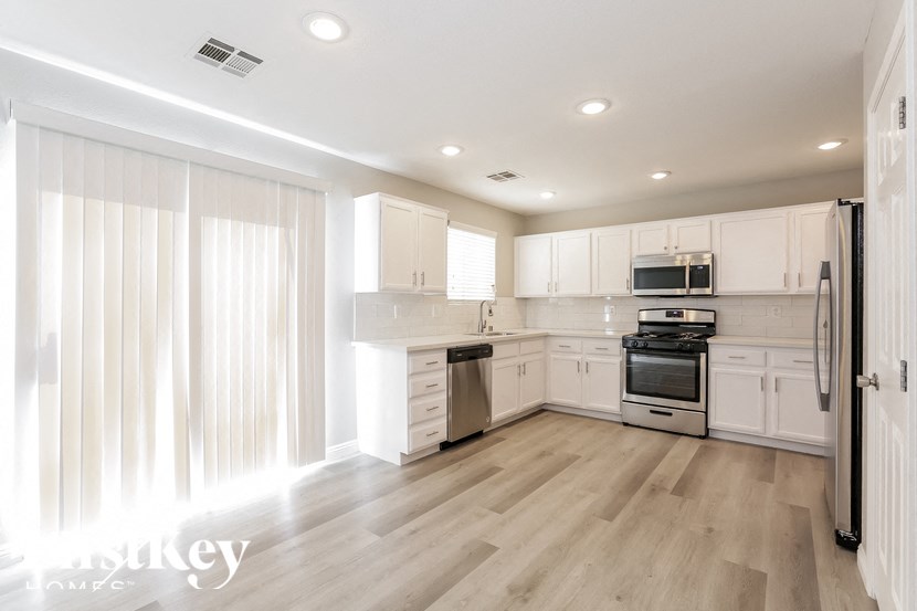 A modern kitchen with white cabinets and appliances.