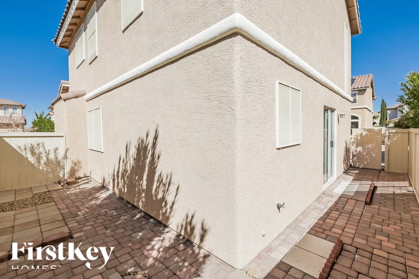 A beige stucco house with a brick walkway in front.