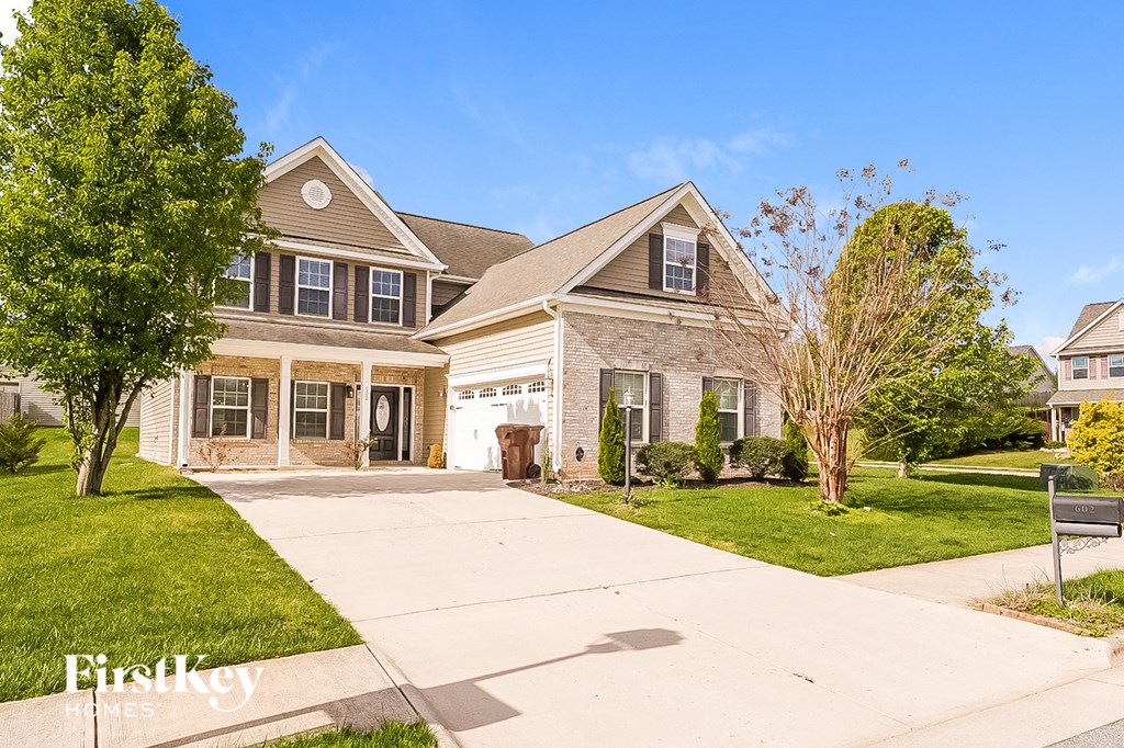 a white and brick house with a sidewalk in front of it