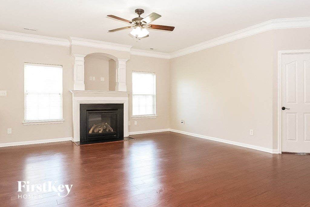 a empty living room with a fireplace and a ceiling fan