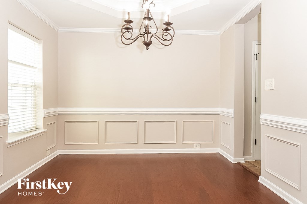 a dining room with white wainscoting and a chandelier