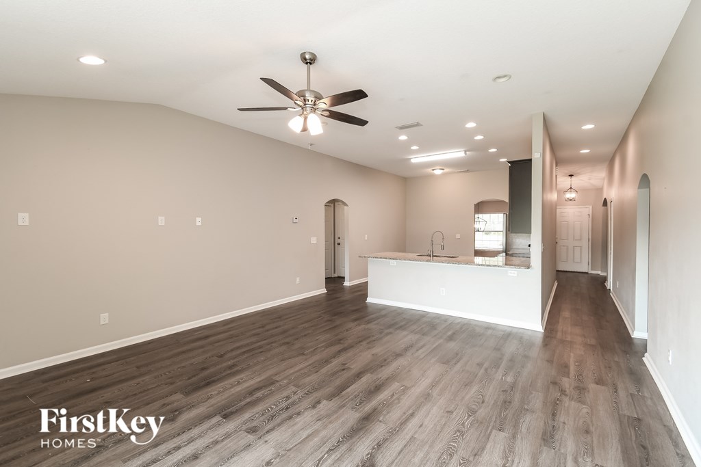 A spacious room with a ceiling fan and wooden flooring.