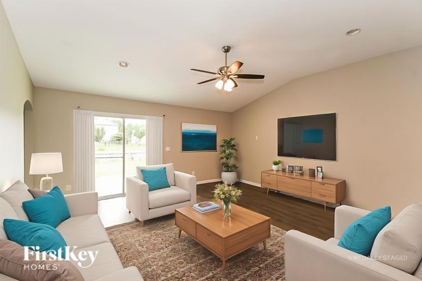 A living room with a white couch, a wooden coffee table, and a flat screen TV mounted on the wall.
