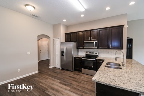 A kitchen with a refrigerator, oven, and sink.
