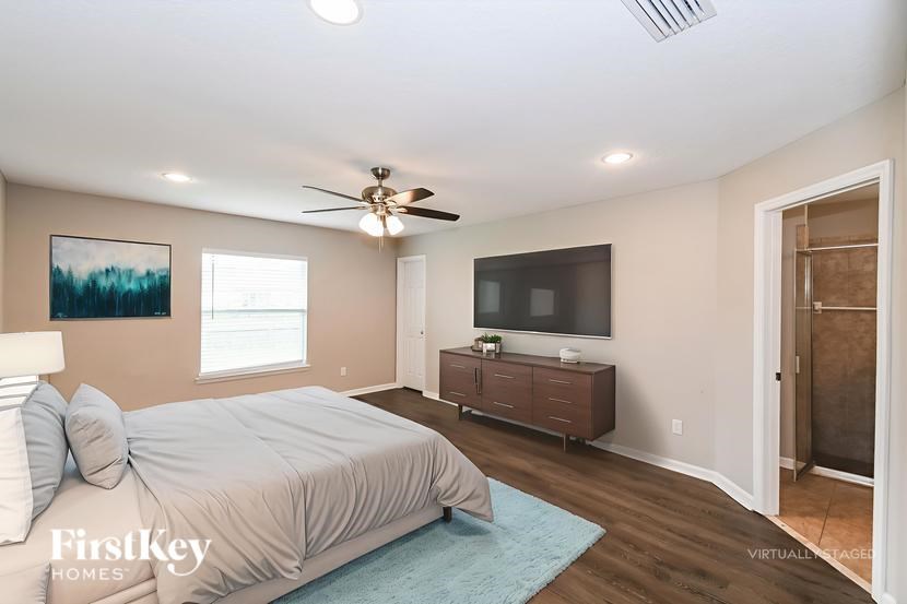 A bedroom with a bed, a television, and a ceiling fan.
