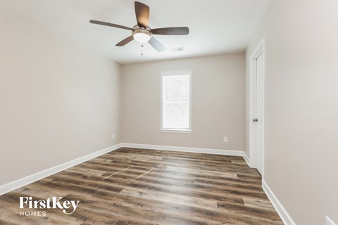 the spacious living room with wood floors and a ceiling fan