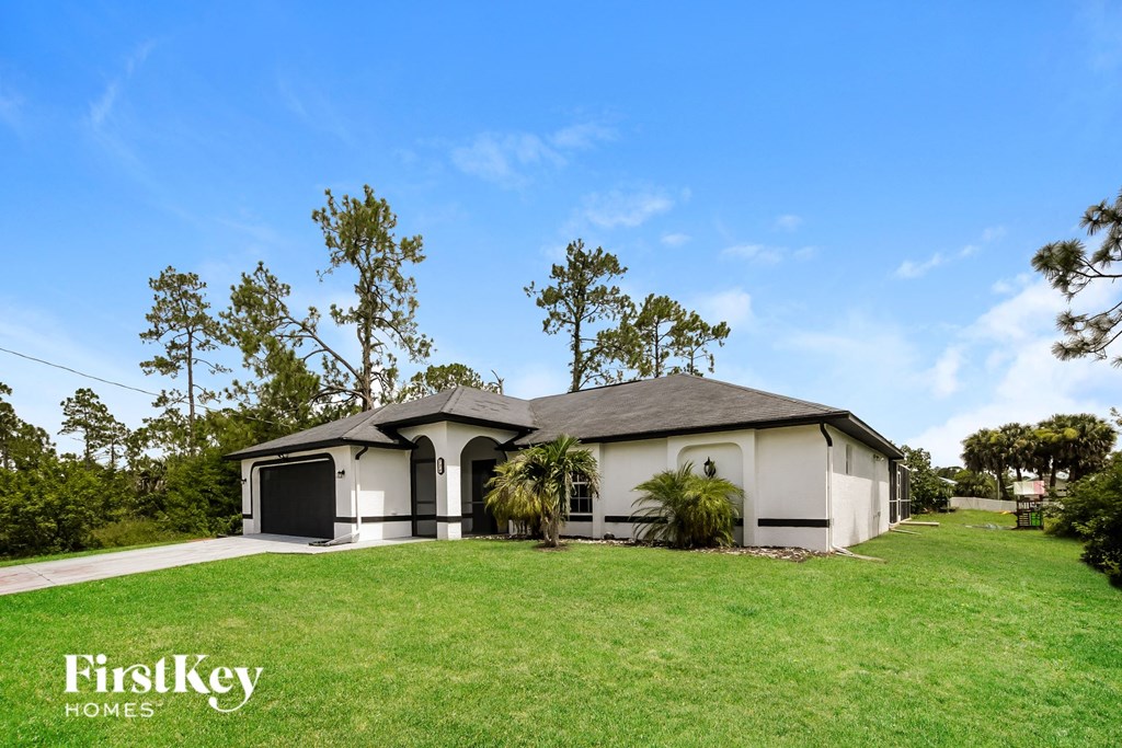 a white house with a lawn and palm trees