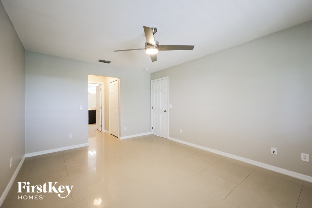 an empty living room with a ceiling fan and white walls