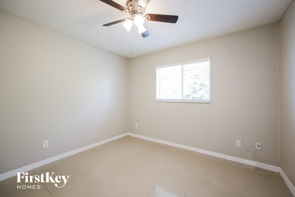 an empty room with a ceiling fan and a window