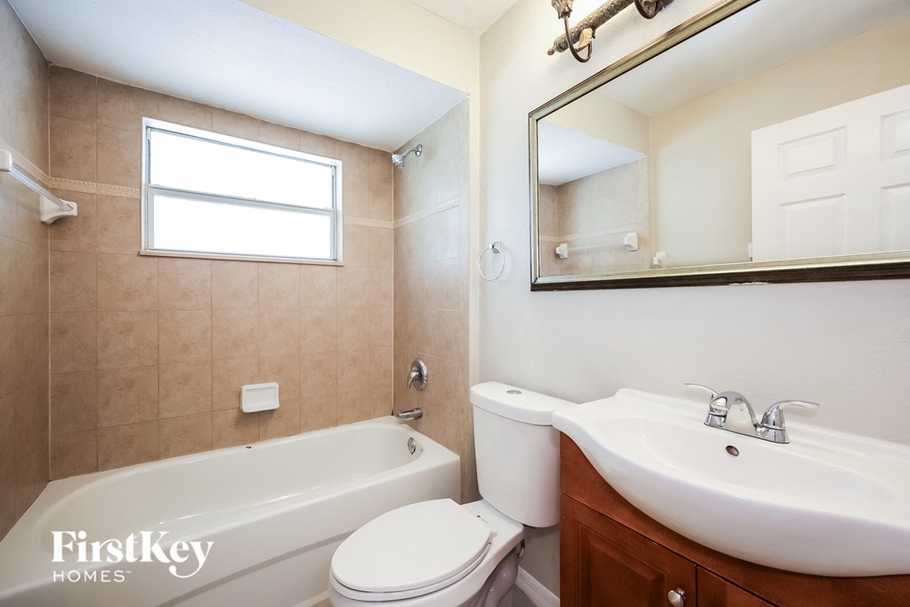 a bathroom with a toilet sink and tub and a mirror