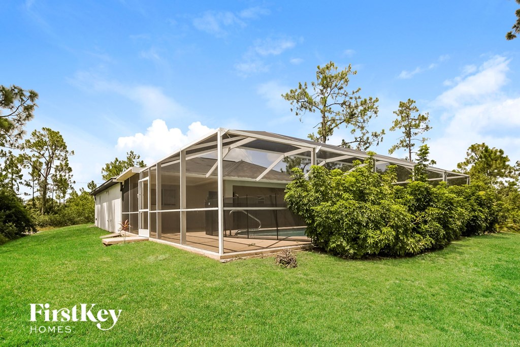 a glass house on a green lawn with trees