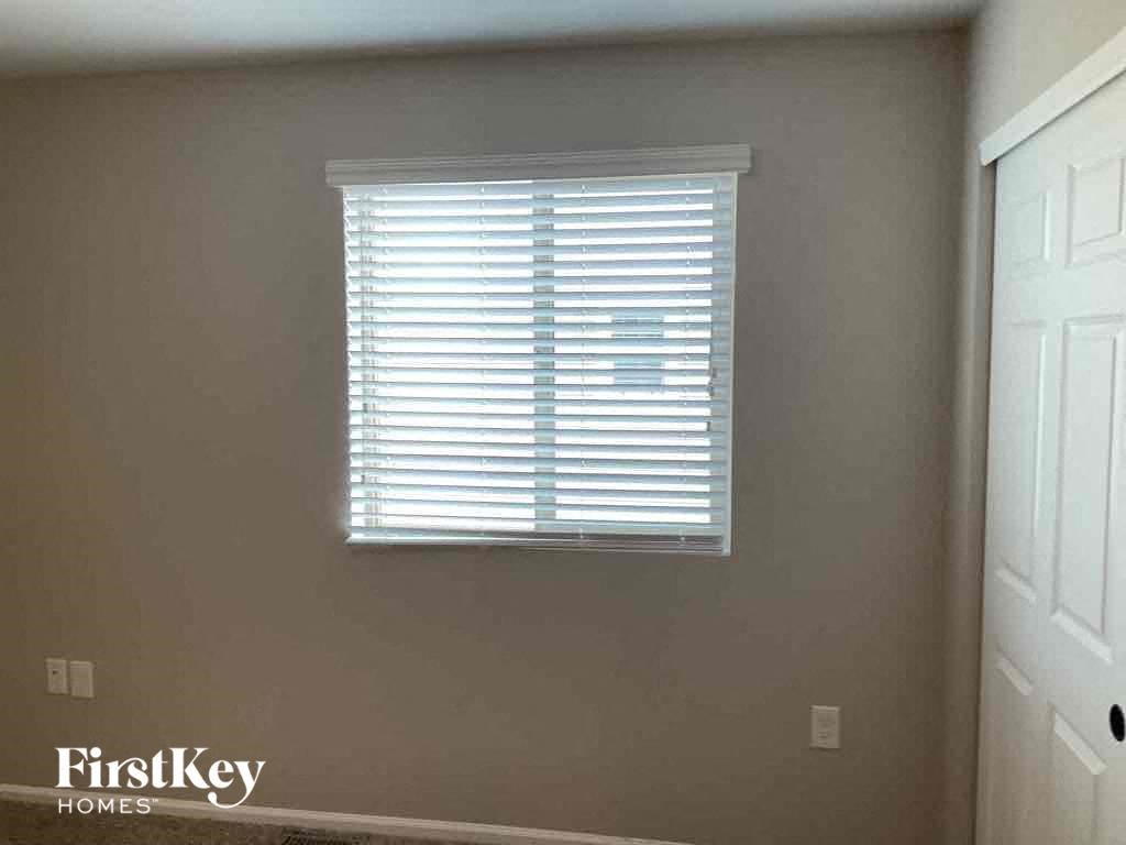 a window with white blinds in a room with a door