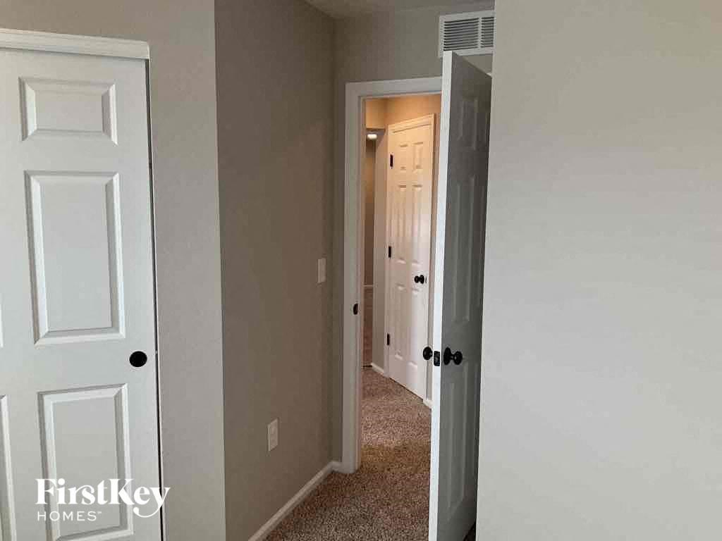 an empty hallway with a door open to a closet and a door to a bedroom