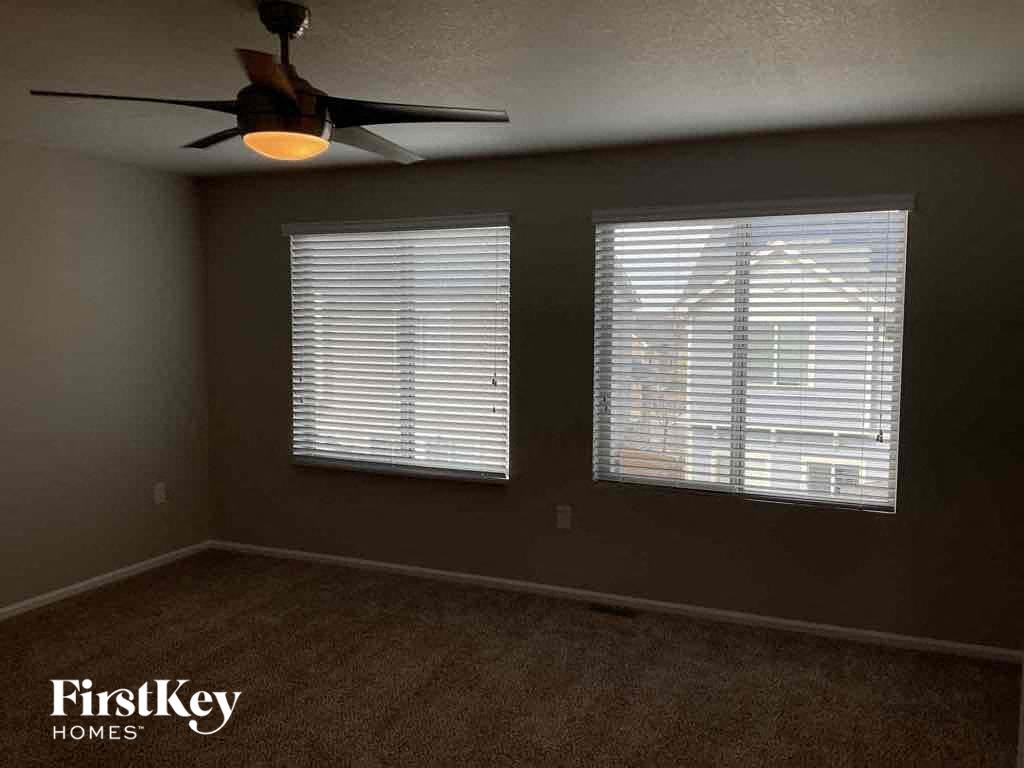 a living room with a ceiling fan and two windows