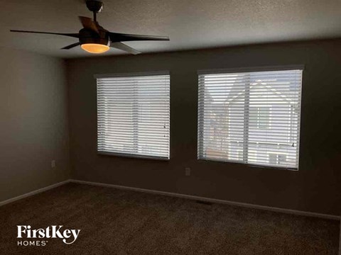 a living room with a ceiling fan and two windows