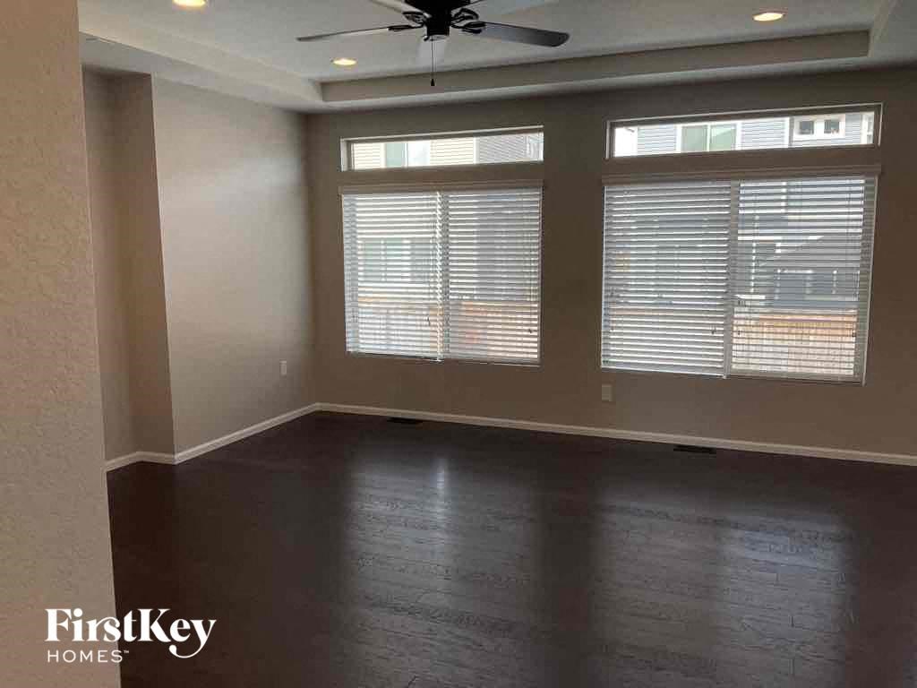 an empty living room with wood floors and a ceiling fan