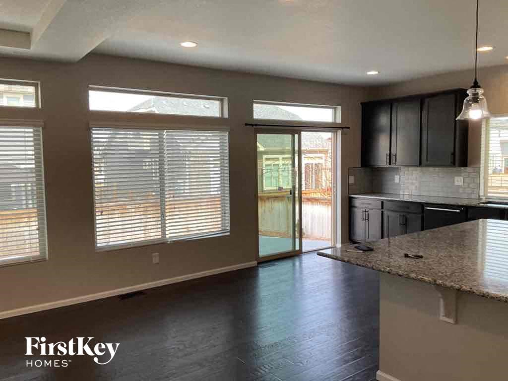 an empty living room with a kitchen and a door to a patio