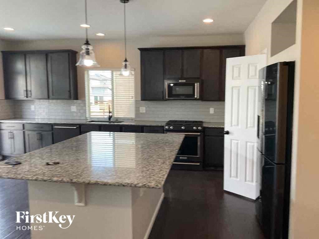a kitchen with black cabinets and a marble counter top