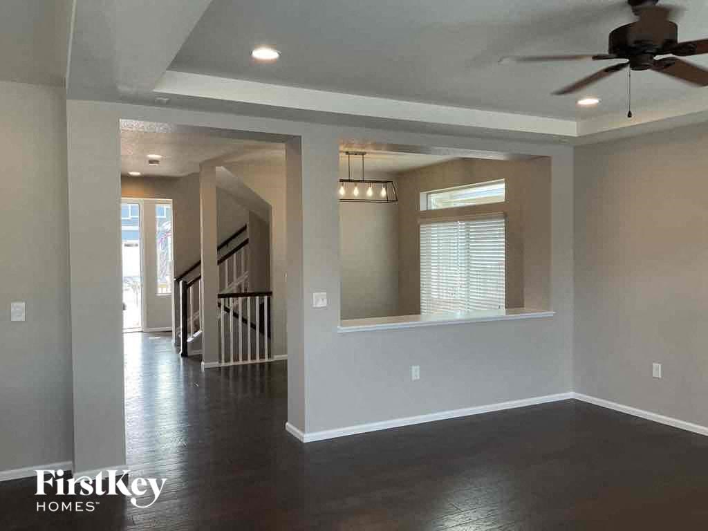 an empty living room with a ceiling fan and a window